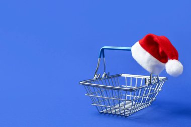 Mavi arka planda Noel Baba şapkası olan alışveriş sepeti.