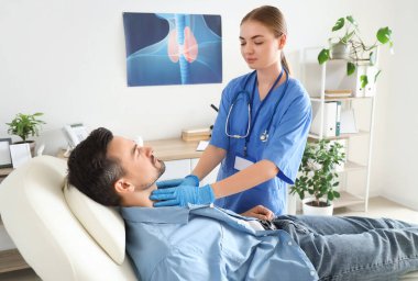 Kadın endokrinolog klinikte erkeğin tiroid bezini inceliyor.