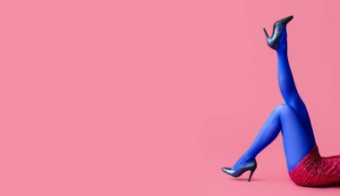 Pembe arka planda mavi taytlı genç ve güzel bir kadın.