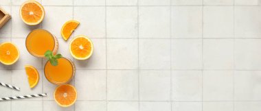 Taze portakal suyu bardakları ve beyaz fayansla kesilmiş meyveler.