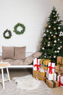 Oturma odasının içinde kanepe, Noel çelengi ve köknar ağacı var.
