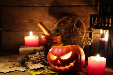 Cadılar Bayramı kompozisyonu kriko-fener, yanan mumlar, eski parşömenler ve ahşap masa üzerindeki yapraklar, yakın çekim