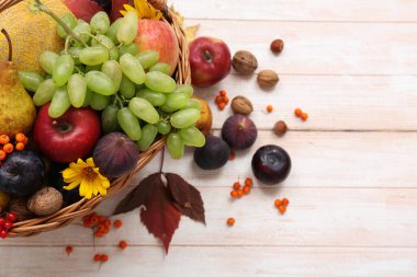 Beyaz ahşap arka planda farklı taze meyvelerle dolu sepet.