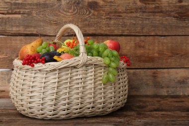 Tahta arka planda farklı taze meyvelerle dolu sepet.