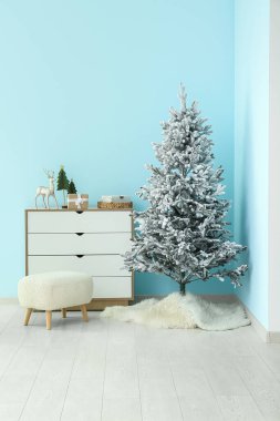 Güzel bir Noel ağacı. Mavi duvarın yanında çekmeceleri ve minderleri var.