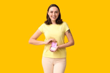 Sarı arka planda tampon saklama kutusu olan güzel genç bir kadın.