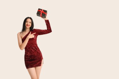 Beyaz arka plandaki bir şeyi gösteren hediye kutusuyla güzel, şık bir kadın. Kara Cuma İndirimi