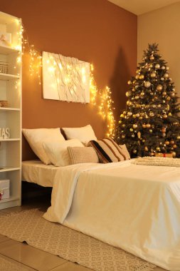 Parlayan ışıkları, boyası ve Noel ağacı olan yatak odasının içi.