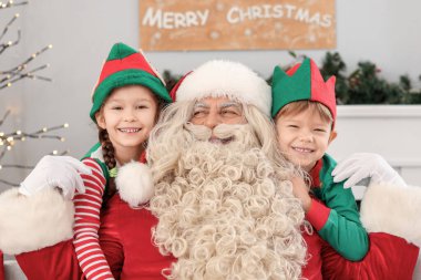 Noel arifesinde Noel Baba 'yı kucaklayan küçük elfler.