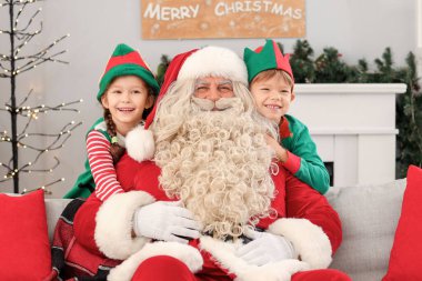 Noel arifesinde Noel Baba 'yı kucaklayan küçük elfler.