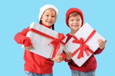 Mavi arka planda Noel hediyeleri olan şirin çocuklar.