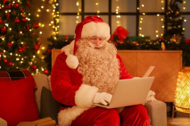 Noel arifesinde evde dizüstü bilgisayarı ve mektubu olan Noel Baba.