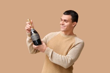 Bir şişe şampanyası olan genç adam kahverengi arka planda Noel 'i kutluyor.