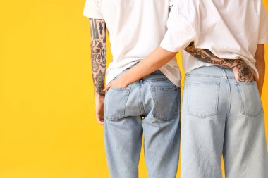 Sarı arka planda şık kotlu genç bir çift.