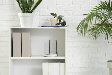 Ofiste kablosuz ağ yönlendiricisi, bitki ve dizinleri olan raf ünitesi