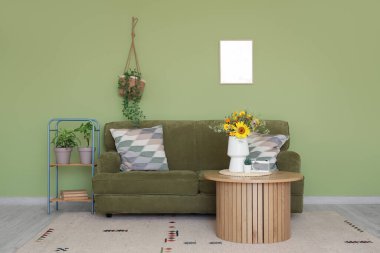 Rahat kanepe ve vazodaki yabani çiçekler oturma odasındaki sehpanın üzerinde.