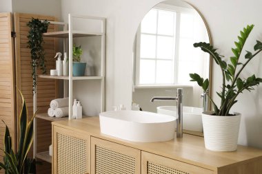 Interior of light bathroom with sink, chest of drawers and mirror