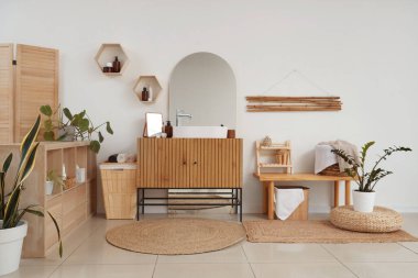 Modern lavabo, bank, dolap ve katlanan ekran, banyonun iç tarafındaki beyaz duvarın yanında.