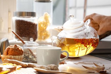 Çaydanlıktan fincana çay dolduran kadın eller masadaki kekin yanında. Yakın çekim.