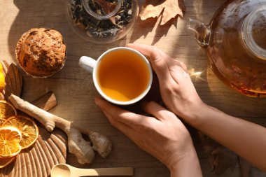 Çaydanlığın yanında yeşil çay ve masada kek olan kadın eller. Üst görünüm