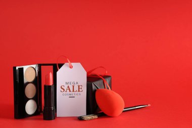 Dekoratif kozmetik ürünleri, makyaj malzemeleri, satış etiketi ve kırmızı arka planda hediye kutusu.