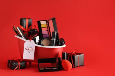 Dekoratif kozmetik ürünleri, hediye kutuları ve kırmızı arka planda satış etiketi olan küçük küvet.