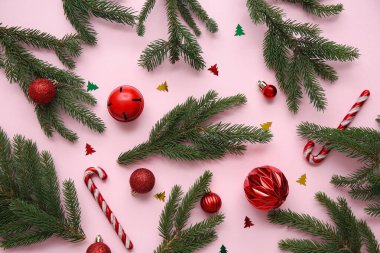 Pembe arka planda Noel dalları, toplar ve şeker kamışları olan kompozisyon. Üst görünüm