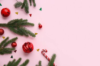 Pembe arka planda Noel dalları, toplar ve şeker kamışları olan kompozisyon. Üst görünüm