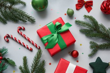 Firavun ağacı dalları, hediye kutuları ve gri arka planda Noel dekoru. Üst görünüm