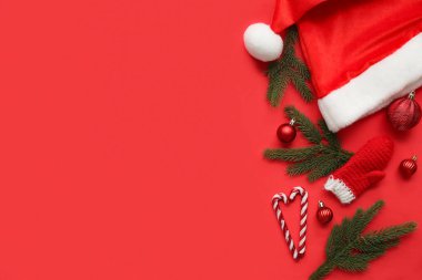 Köknar ağacı dalları ve kırmızı arka planda Noel süslemeleri olan kompozisyon. Üst görünüm