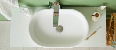 Banyoda beyaz lavabo, kozmetik ve diş fırçası var.