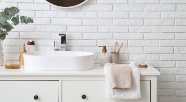 Modern lavabo ve banyo malzemeleri banyoda beyaz tuğla duvarın yanında duruyor.