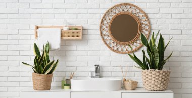 Modern lavabosu ve hasır aynası olan hafif bir banyo.