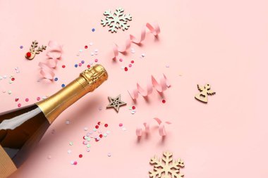 Pembe arka planda bir şişe şampanya ve dekor olan Noel kompozisyonu, yakın plan.