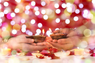 Kırmızı arka planda Diwali (Işık Festivali) için Diwali lambaları tutan Hintli kadınların elleri