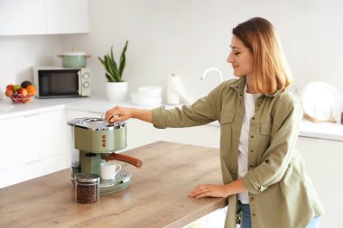 Genç bayan mutfakta kahve yapıyor.