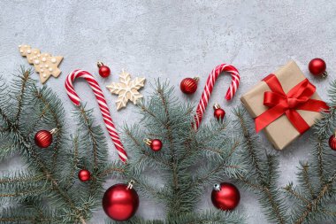 Topları, bastonları ve beyaz arka planda hediye kutusu olan Noel ağacı dalları.