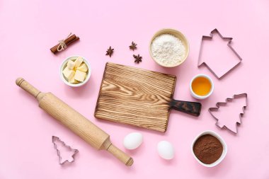 Pembe arka planda Noel kurabiyeleri hazırlamak için mutfak gereçleri ve malzemeleriyle kompozisyon