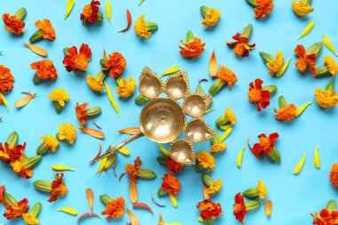 Diya lamp with marigold flowers on blue background. Divaly celebration clipart