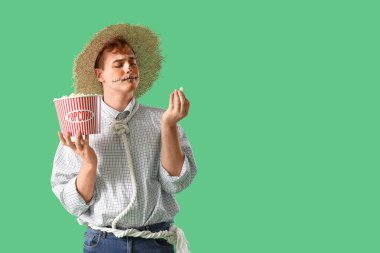 Cadılar Bayramı için giyinmiş genç adam ve yeşil arka planda patlamış mısır.