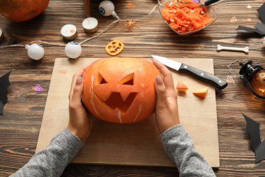 Ahşap masada oyulmuş Cadılar Bayramı kabağı olan kadın.