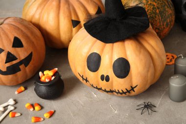 Gri grunge masasında boyanmış balkabakları ve Cadılar Bayramı süslemeleri