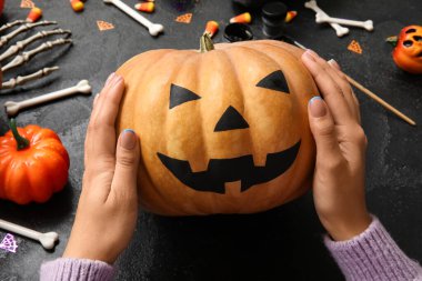 Siyah Grunge masasında boyalı Cadılar Bayramı kabağı olan kadın.