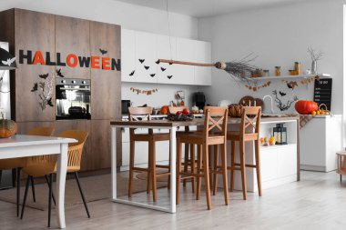 Cadılar Bayramı için beyaz tezgah ve yemek masasıyla dekore edilmiş hafif mutfağın içi.