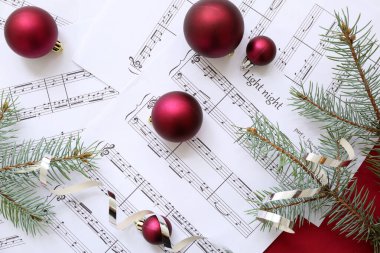 Kırmızı arka planda Noel dekoru olan nota kağıtları