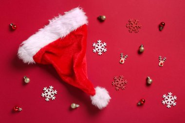 Kırmızı arka planda Noel Baba şapkası ve Noel süslemeleri