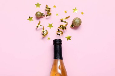 Açık pembe arka planda bir şişe alkol ve altın madalyayla güzel bir yeni yıl partisi kompozisyonu..