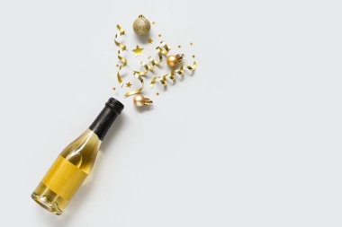 Gri arka planda yeni yıl partisi için bir şişe şampanya ve dekorasyonla harika bir kompozisyon.