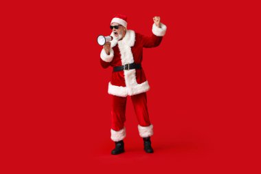 Kırmızı arka planda megafonla bağıran güneş gözlüklü Noel Baba.