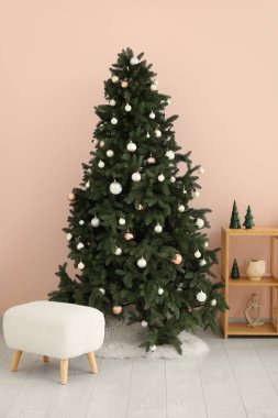Güzel Noel ağacı, raf ünitesi ve pouf pembe duvarın yanında.